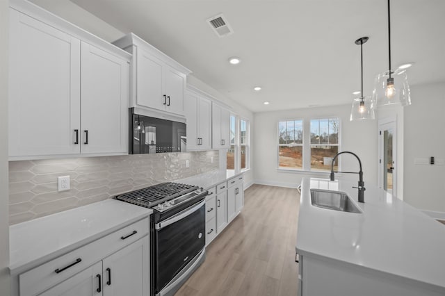 kitchen with white cabinetry, tasteful backsplash, sink, hanging light fixtures, and stainless steel range with gas stovetop