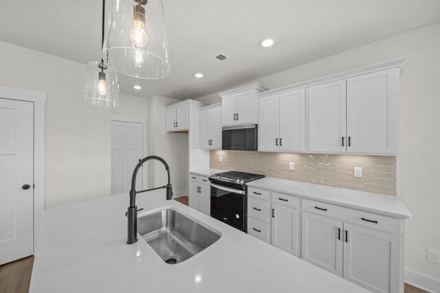 kitchen featuring decorative light fixtures, white cabinetry, sink, backsplash, and stainless steel range with gas stovetop