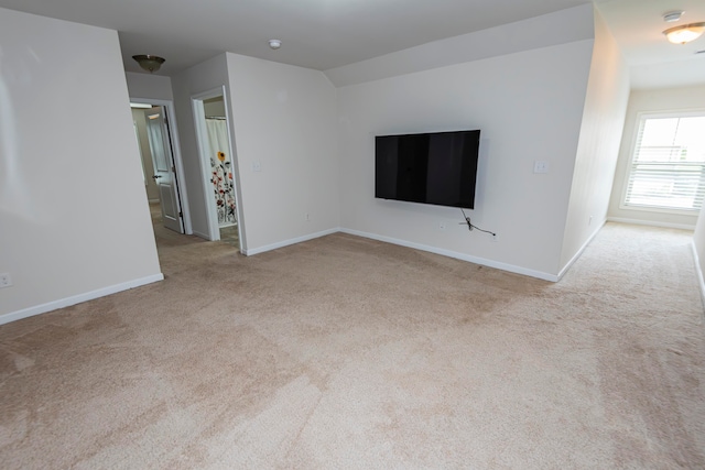 unfurnished living room featuring light colored carpet and vaulted ceiling