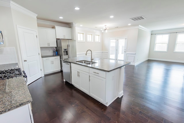 kitchen with sink, white cabinets, appliances with stainless steel finishes, and a kitchen island with sink