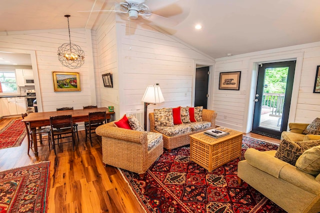 living room with wooden walls, lofted ceiling, dark wood-type flooring, and a wealth of natural light