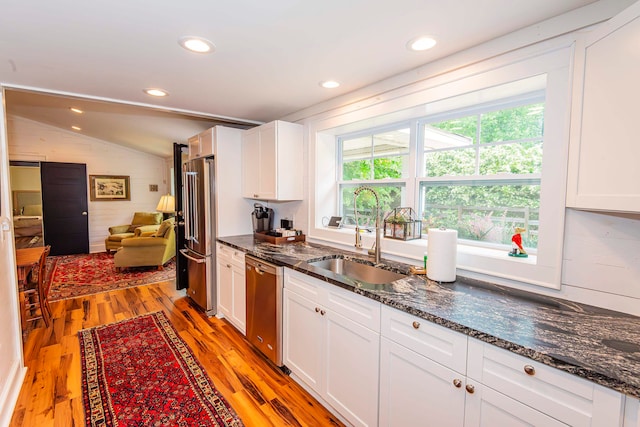 kitchen with light hardwood / wood-style floors, white cabinetry, stainless steel appliances, lofted ceiling, and sink