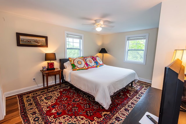 bedroom with multiple windows, wood-type flooring, and ceiling fan