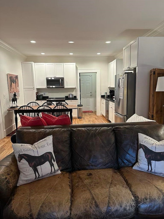 kitchen with ornamental molding, stainless steel appliances, white cabinets, and hardwood / wood-style floors