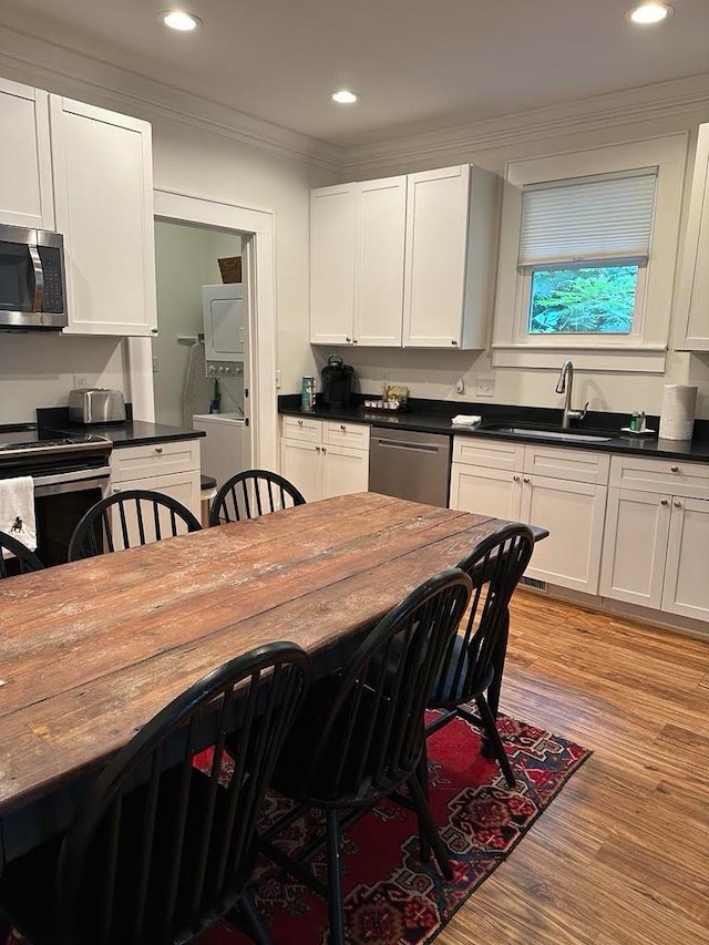 kitchen featuring a breakfast bar, light wood-type flooring, white cabinetry, appliances with stainless steel finishes, and ornamental molding