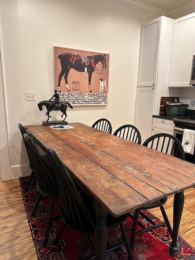 dining space with light wood-type flooring and crown molding