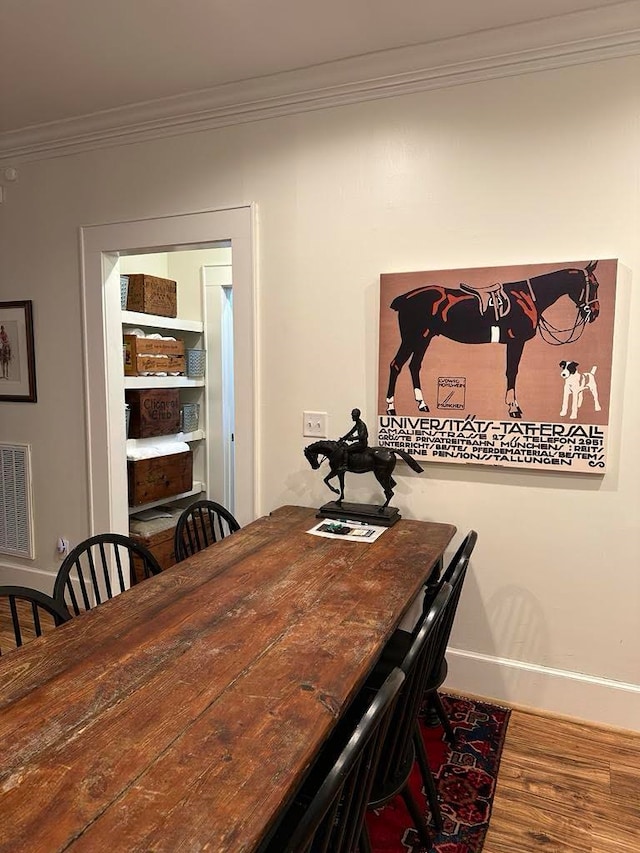 dining room with wood-type flooring and crown molding