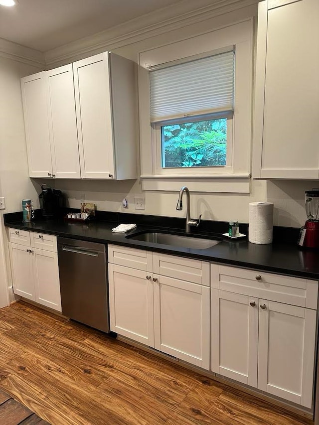 kitchen featuring hardwood / wood-style flooring, stainless steel dishwasher, sink, and white cabinets