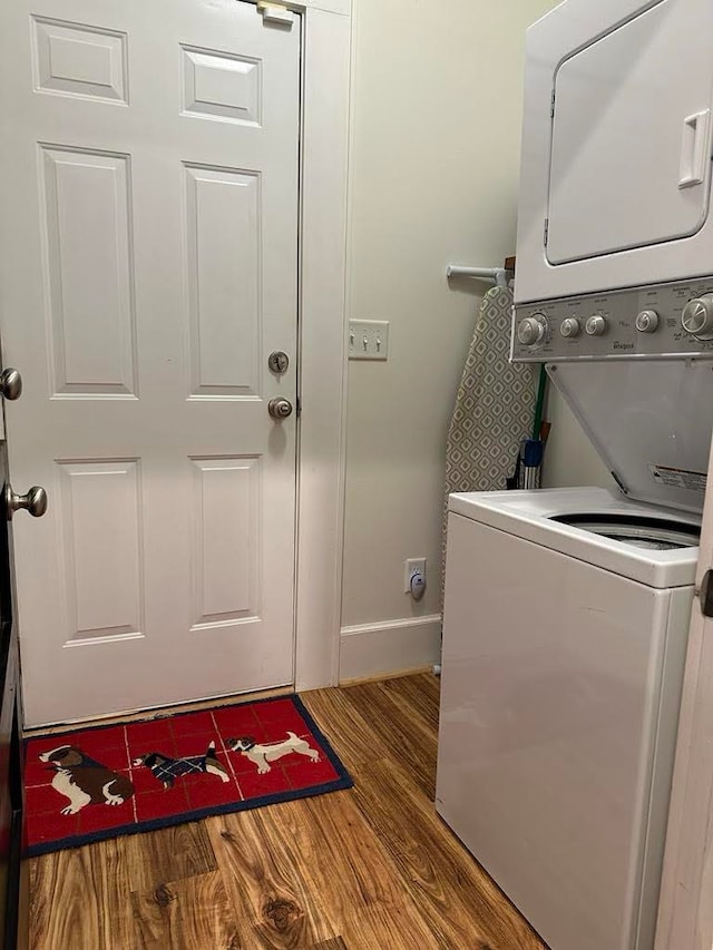 laundry area with stacked washer and dryer and hardwood / wood-style flooring