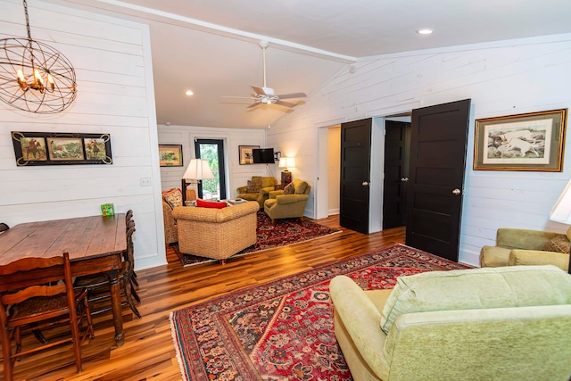 living room featuring ceiling fan with notable chandelier, vaulted ceiling, wood walls, and hardwood / wood-style floors