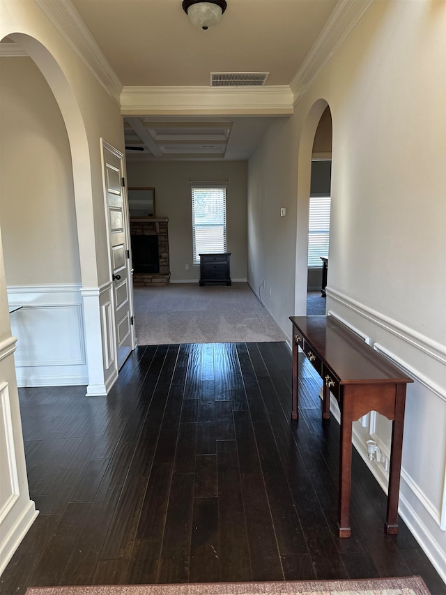 hallway with coffered ceiling, beamed ceiling, crown molding, and dark hardwood / wood-style flooring