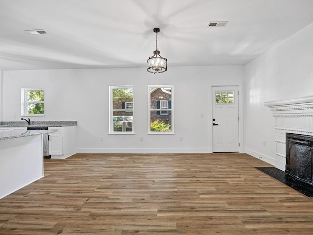 unfurnished living room with a healthy amount of sunlight, hardwood / wood-style floors, and a chandelier