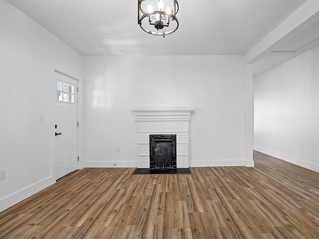 unfurnished living room featuring wood-type flooring, a chandelier, and a fireplace