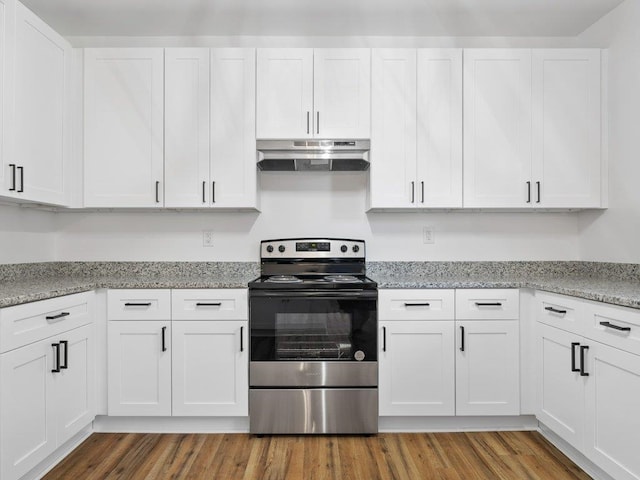 kitchen with stainless steel range with electric cooktop, white cabinetry, light stone counters, and hardwood / wood-style flooring