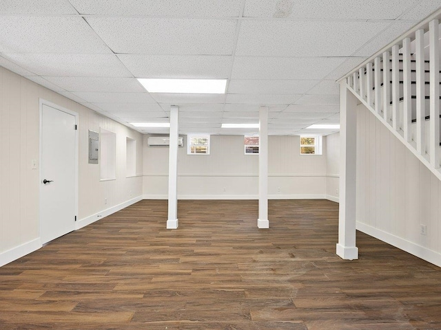 basement featuring a paneled ceiling, dark hardwood / wood-style floors, and a wall mounted AC