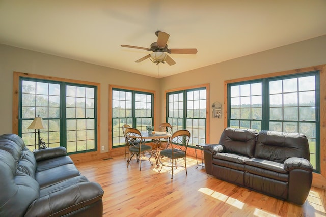 living room with light hardwood / wood-style flooring, ceiling fan, and a healthy amount of sunlight