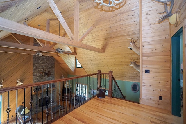 interior space with high vaulted ceiling, wooden walls, beamed ceiling, and hardwood / wood-style flooring