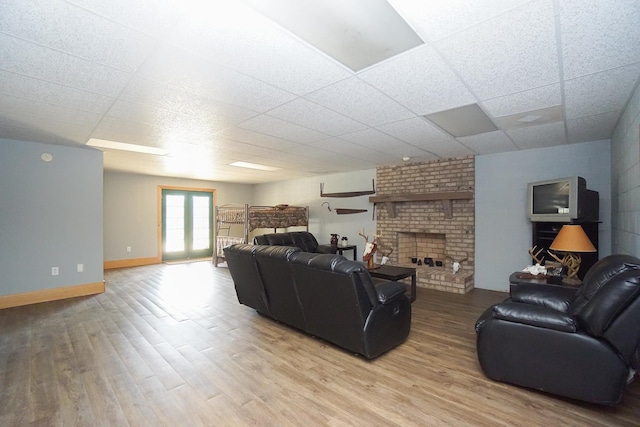 living room with light wood-type flooring, a fireplace, and a drop ceiling