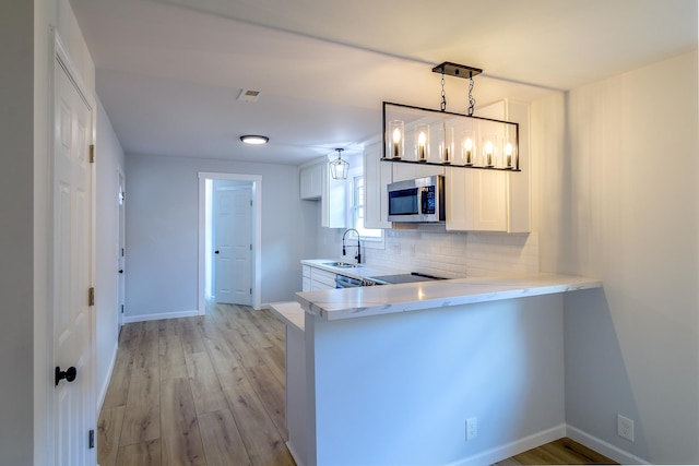 kitchen with pendant lighting, white cabinetry, kitchen peninsula, and light hardwood / wood-style flooring