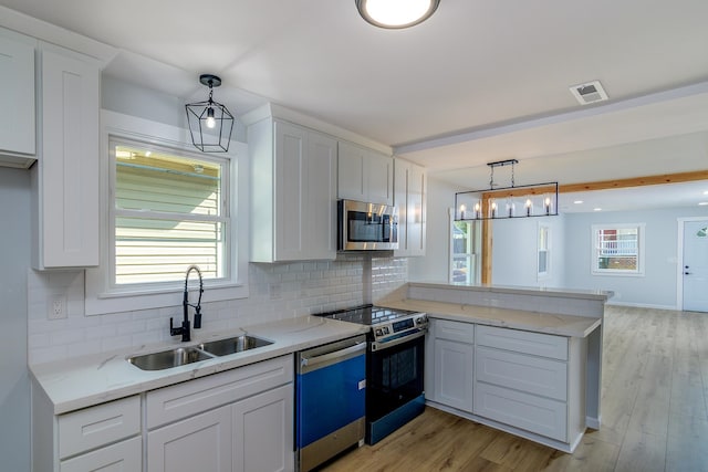 kitchen with white cabinets, appliances with stainless steel finishes, pendant lighting, and sink