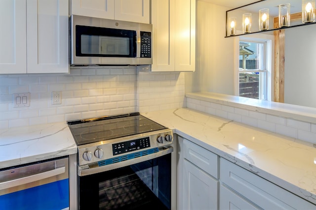 kitchen featuring pendant lighting, tasteful backsplash, white cabinets, appliances with stainless steel finishes, and light stone countertops