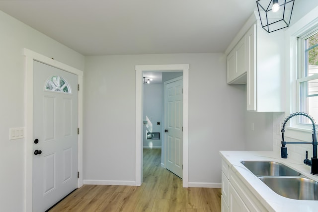 kitchen with white cabinets, light wood-type flooring, and sink