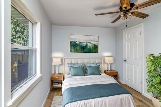 bedroom with ceiling fan, light hardwood / wood-style flooring, and multiple windows