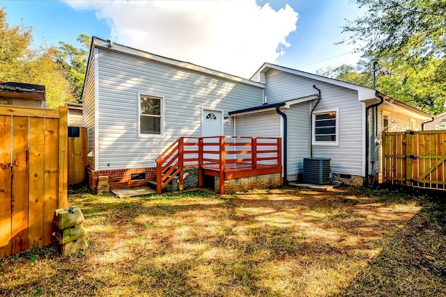 rear view of house with central AC, a deck, and a yard