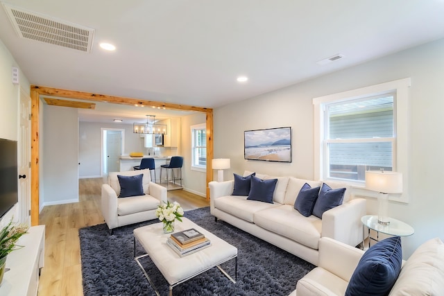 living room featuring light wood-type flooring and a notable chandelier