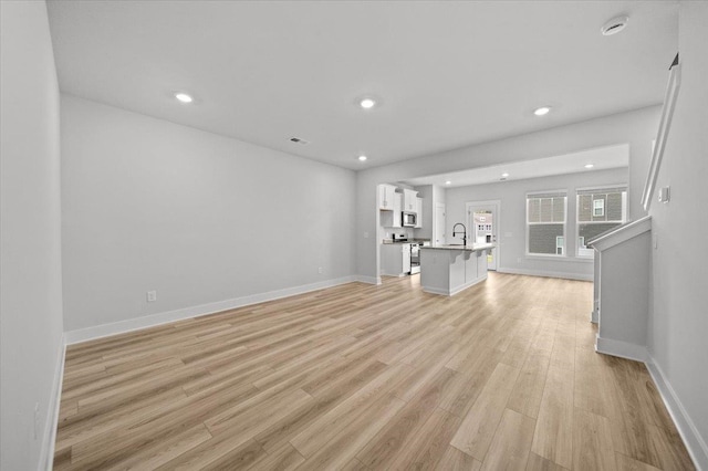 unfurnished living room featuring light hardwood / wood-style floors and sink