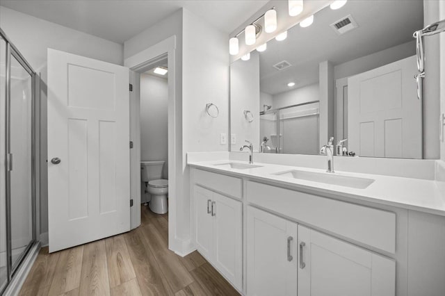 bathroom with vanity, a shower with shower door, toilet, and hardwood / wood-style flooring