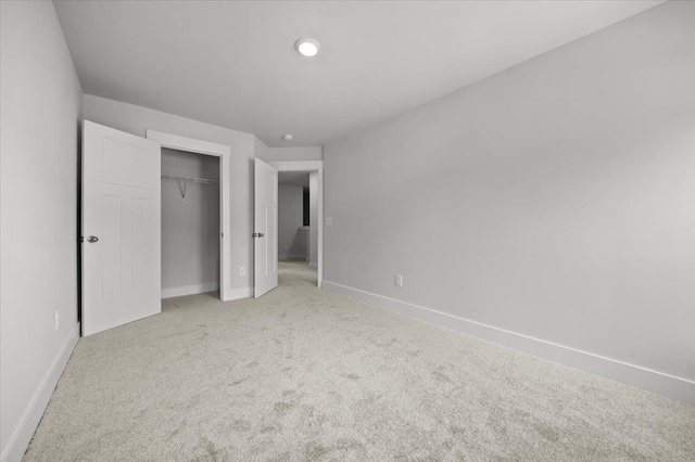 unfurnished bedroom featuring light carpet and a closet