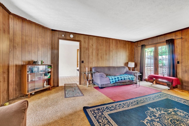 living room featuring a textured ceiling, wood walls, carpet flooring, and crown molding