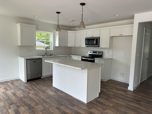 kitchen with a kitchen island, dark hardwood / wood-style flooring, pendant lighting, white cabinetry, and appliances with stainless steel finishes