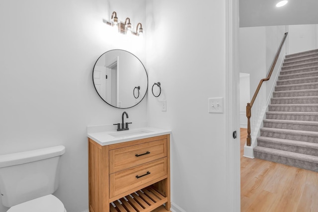 bathroom with wood-type flooring, vanity, and toilet