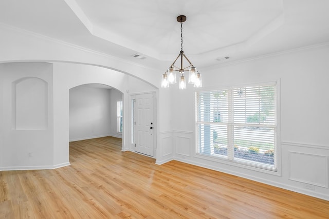 unfurnished room featuring an inviting chandelier, a tray ceiling, crown molding, and light hardwood / wood-style floors