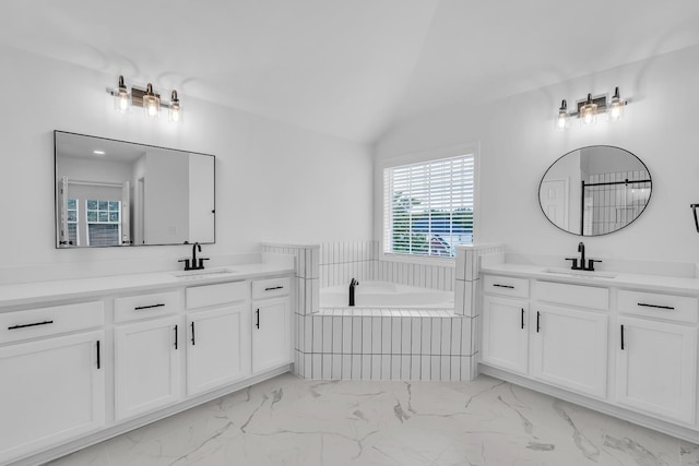 bathroom with lofted ceiling, tiled bath, and vanity