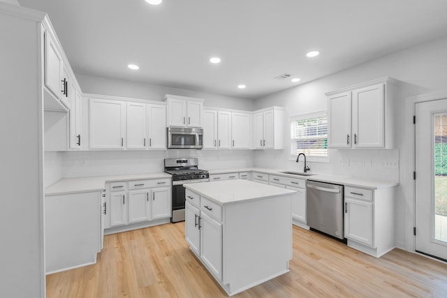 kitchen featuring a kitchen island, appliances with stainless steel finishes, light wood-type flooring, and white cabinetry