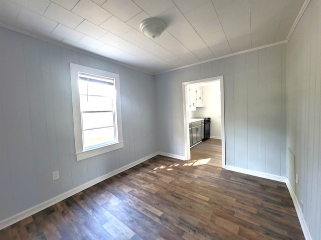 unfurnished room featuring wooden walls, dark hardwood / wood-style floors, and ornamental molding