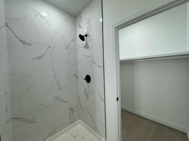 bathroom featuring wood-type flooring and a tile shower