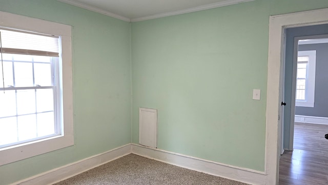 spare room with a healthy amount of sunlight, crown molding, and hardwood / wood-style floors