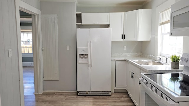 kitchen featuring white appliances, sink, light wood-type flooring, and a healthy amount of sunlight