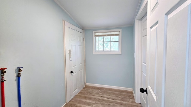 hall with crown molding, vaulted ceiling, and light hardwood / wood-style flooring