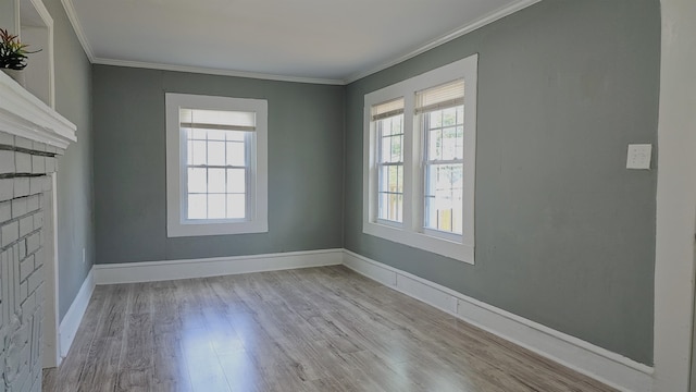 empty room with crown molding, a wealth of natural light, and light hardwood / wood-style flooring