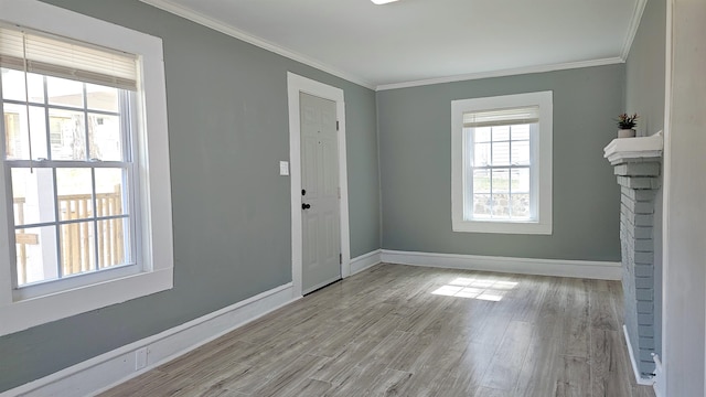 entryway with light wood-type flooring, crown molding, and a fireplace