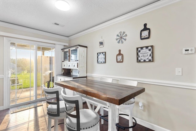 dining room with ornamental molding, hardwood / wood-style floors, and a textured ceiling