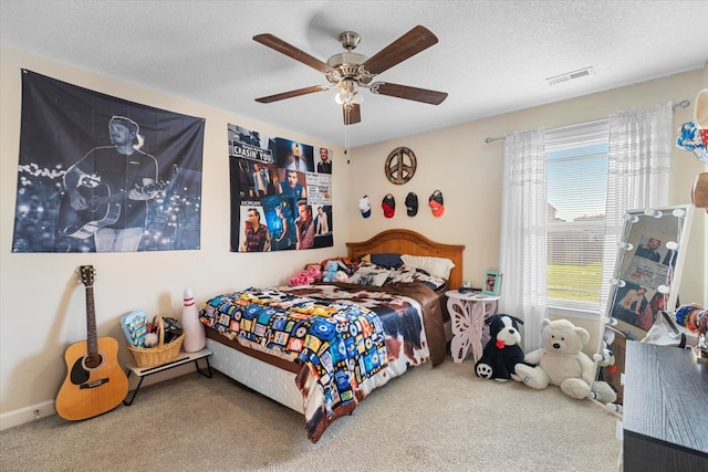 carpeted bedroom with ceiling fan and a textured ceiling