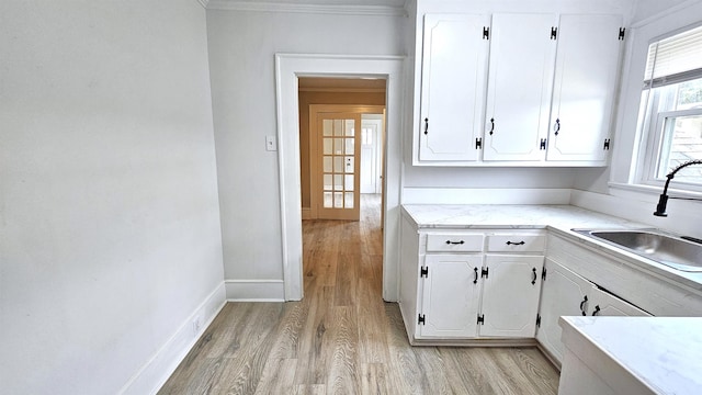 kitchen featuring light hardwood / wood-style floors, crown molding, sink, and white cabinetry