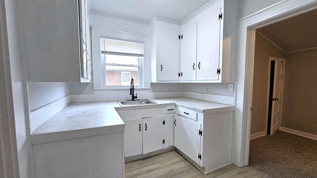 kitchen with light hardwood / wood-style flooring, crown molding, sink, and white cabinetry