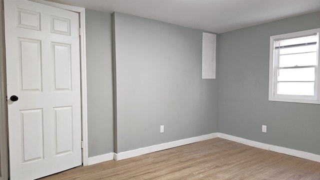 empty room featuring electric panel and light hardwood / wood-style flooring